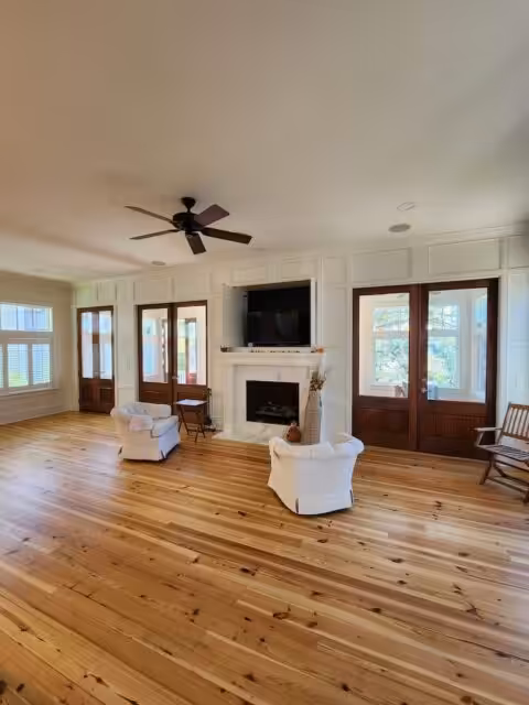 The Best Paint Finish for Walls, Room by Room Living room with white walls, wood floors, a fireplace and tall French doors