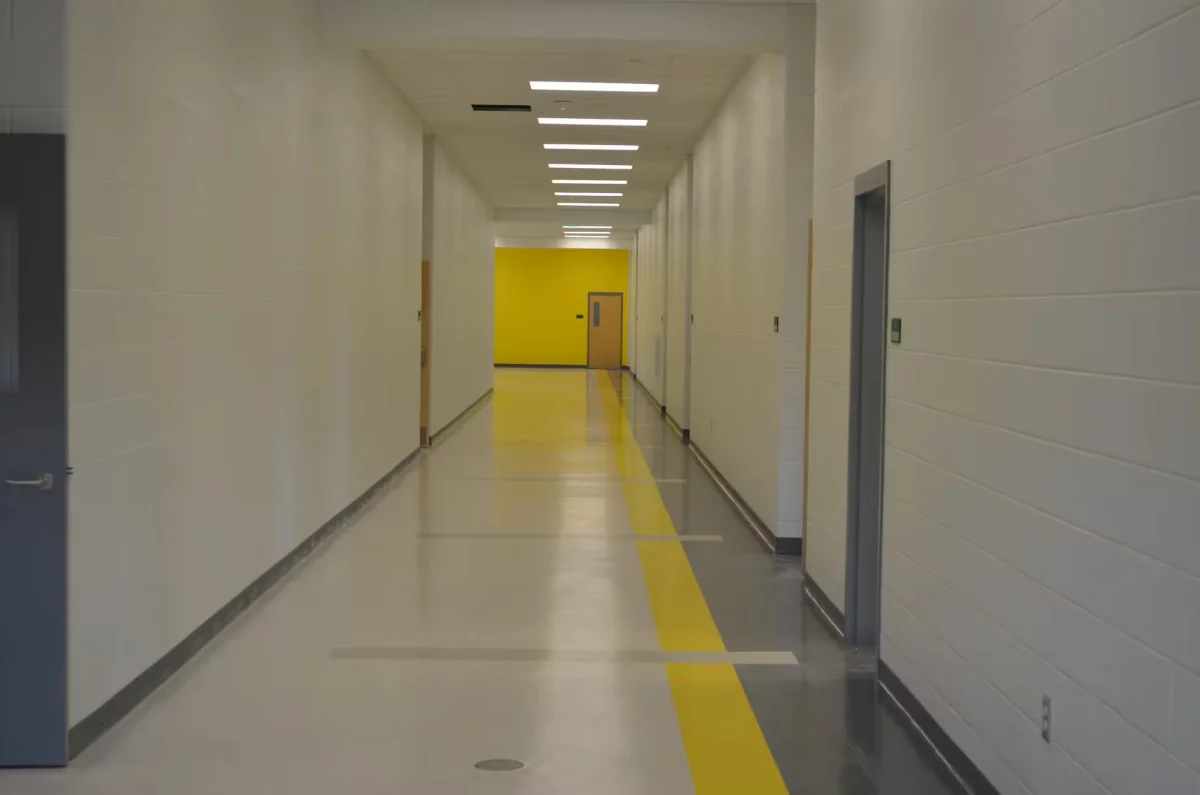 Long hallway with a glossy coated floor and a yellow safety stripe