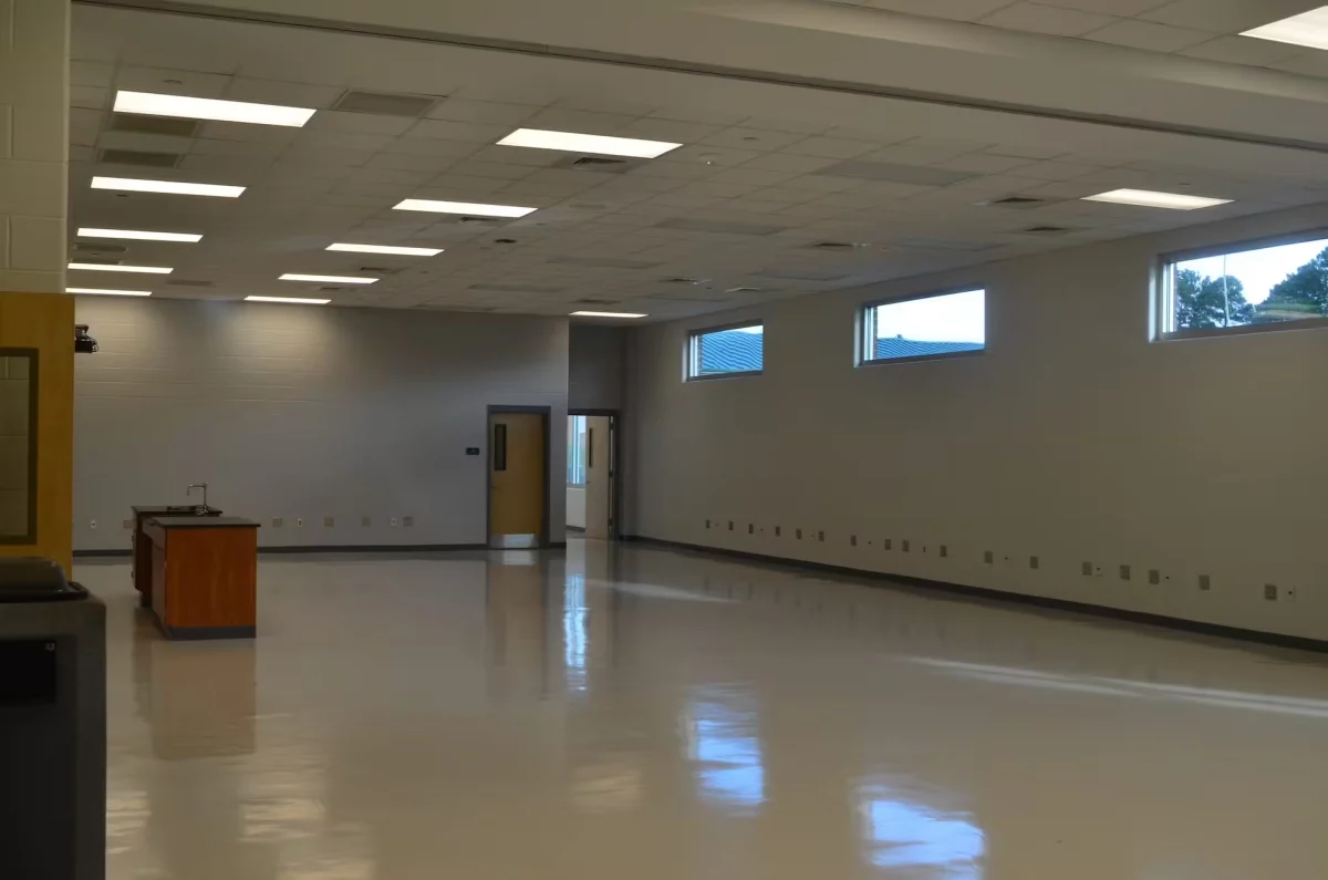 Large empty commercial room with a glossy coated floor reflecting the ceiling lights
