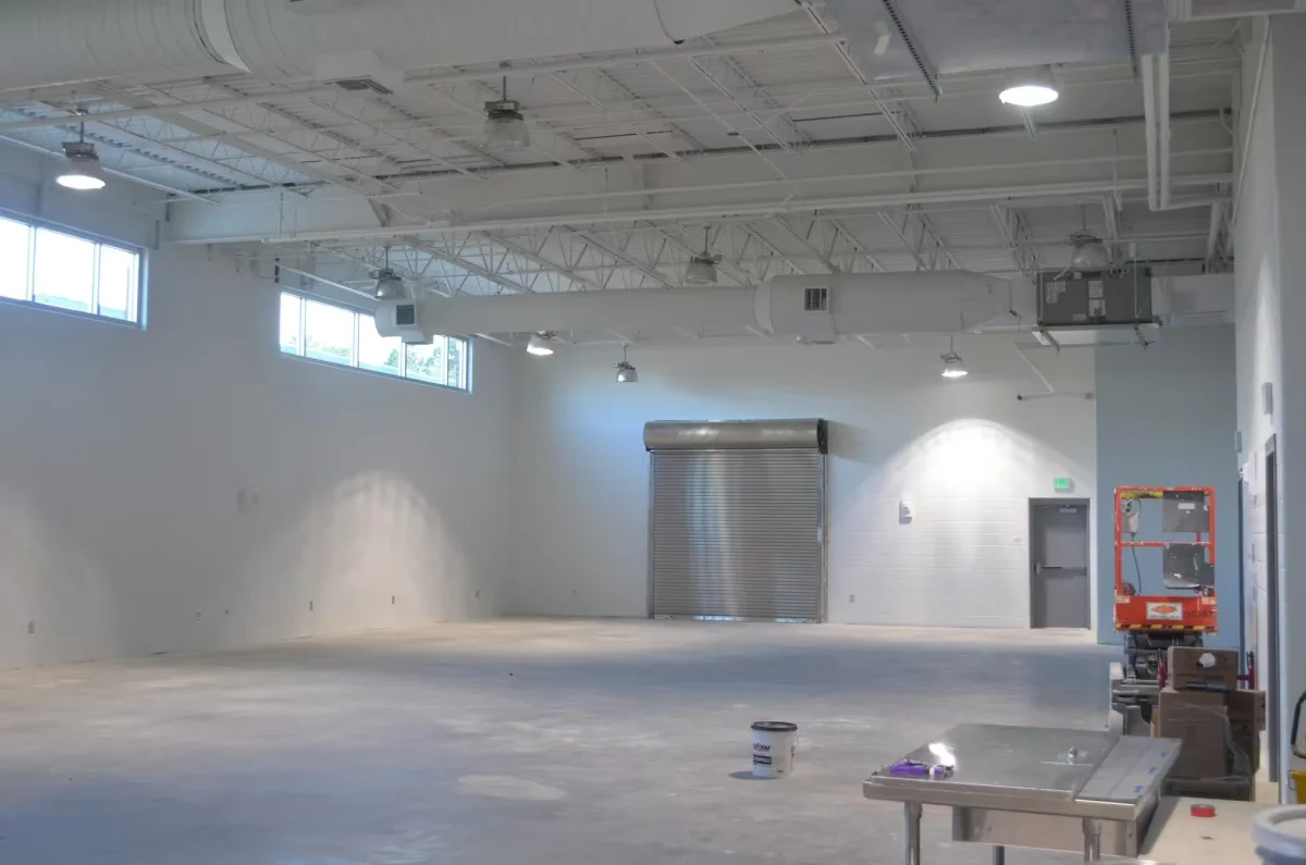 Empty warehouse space with a bare concrete floor, white walls and a roll-up door